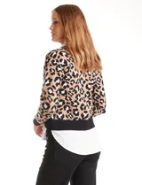 Buzo de la marca Ninety con estampado animal print en tonos beige, negro y blanco. Presenta cuello en V con solapa y botones frontales, simulando una camisa blanca debajo. Las mangas son largas y el ruedo también simula el de una camisa.