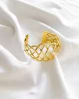 Pulsera dorada rígida con diseño calado de líneas entrecruzadas.