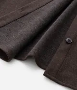 Camisa de corte largo tipo shacket, confeccionada en polivelour color marrón. Presenta cuello camisero, cierre frontal con botones, hombros caídos, mangas largas y dos bolsillos frontales aplicados con solapa.