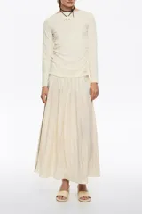 Falda midi color crema de corte línea A con vuelo, cremallera lateral invisible y pliegues irregulares cosidos en la cintura.