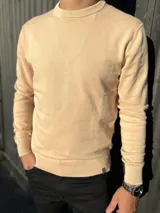 Sweater de punto fino de algodón, color beige, con cuello redondo y mangas largas con puños elásticos.