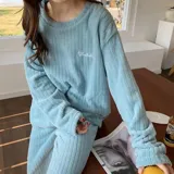 Conjunto de pijama de dos piezas confeccionado en tela de plush texturizada con diseño de rayas verticales en relieve. Incluye una remera de manga larga con cuello redondo y un pantalón de corte holgado. La remera presenta un pequeño bordado decorativo en el pecho.