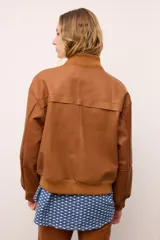Chaqueta de cuero estilo bomber, con cuello alto, puños y cintura de tejido de punto acanalado. Presenta cierre frontal con cremallera y dos bolsillos laterales con solapa.