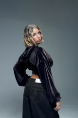 Canguro negro de terciopelo con mangas abullonadas, puños ajustados y cierre metálico frontal.