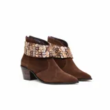 Botas cortas de gamuza color marrón con punta afinada y taco medio ancho. Cuentan con un aplique desmontable alrededor del tobillo decorado con lentejuelas metálicas.