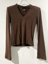 Remera de manga larga color negro, con escote en V y mangas acampanadas tipo Oxford. Confeccionada en tejido de algodón elastizado, con un diseño entallado al cuerpo.