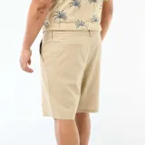 Bermuda estilo chino color beige, con cierre frontal de cremallera, botón y cordón ajustable en la cintura.