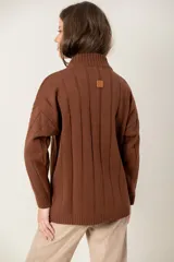Buzo de punto color chocolate con cuello alto, mangas largas y diseño de trenzas verticales. Presenta puños y ruedo acanalados.