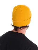 Gorro de lana estilo beanie color amarillo, con tejido de punto acanalado, puño enrollado y pequeña etiqueta negra con el logo de la marca en el lateral.