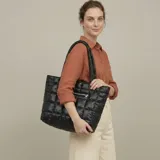Bolso tote negro con diseño acolchado y cierre de cremallera. Tiene dos asas de hombro y un bolsillo frontal con cierre.