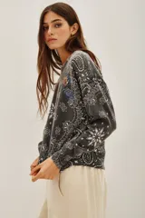 Sweater de punto en color gris oscuro con un diseño integral de estampado tipo bandana en color blanco y detalles gráficos coloridos. Posee cuello redondo, mangas largas y terminaciones acanaladas en puños y cintura.