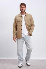 Chaqueta tipo sobrecamisa de algodón color camel, con cuello camisero, cierre frontal de botones oscuros y dos bolsillos de parche con solapa en el pecho.