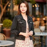 Campera de jean color negro con apliques de perlas en la parte superior frontal. Presenta cuello clásico, cierre frontal con botones metálicos y dos bolsillos en el pecho.