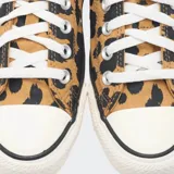 Championes Converse Chuck Taylor All Star de corte bajo, con capellada de lona estampada con diseño de manchas tipo animal print en tonos marrón y negro. Presenta puntera de goma blanca, cordones al tono y suela de caucho con la clásica franja negra.