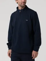 Buzo de cuello alto con medio cierre frontal, confeccionado en algodón orgánico con interior de french terry. Presenta un diseño liso en color azul marino con logo bordado en el pecho y puños acanalados.