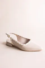 Chatitas destalonadas de cuero charolado color beige con punta fina, taco bajo y detalle de tachas metálicas doradas alrededor del borde.
