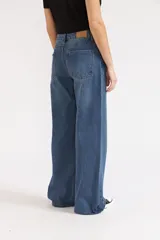 Jeans de mezclilla de corte wide leg, tiro medio y color azul medio con costuras en tono caramelo.