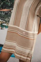 Vestido corto tejido a rayas horizontales en tonos beige y blanco, con cuello redondo y mangas cortas.