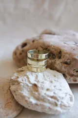 Anillo dorado ancho con tres bandas horizontales separadas por finas líneas.