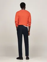 Pantalón chino azul marino de corte cónico, confeccionado en satén de algodón elástico. Cuenta con cierre de cremallera y botón, dos bolsillos laterales abiertos, un pequeño bolsillo delantero en la cintura y dos bolsillos traseros de ojal con botón. Presenta detalles distintivos de Tommy Hilfiger y logo bordado en la parte trasera.