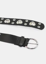 Cinto negro de cuero sintético con ojales redondos y corazones dorados, y hebilla redonda dorada con detalle de corazón.