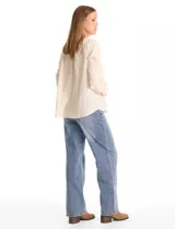 Blusa de algodón azul marino con bordado floral al tono. Presenta escote en V con terminación festoneada y mangas largas ligeramente abullonadas con puños abotonados. Su diseño es de silueta fluida y relajada.