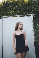 Vestido corto de tela satinada color plata, con diseño tipo corset en el top, breteles finos y falda con volados superpuestos.