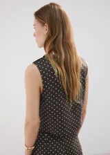 Top crop marrón oscuro con estampado de lunares blancos, cuello redondo y tirantes anchos.