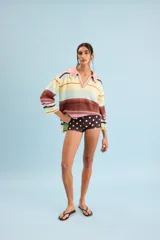 Buzo de algodón tejido, de calce relajado y silueta amplia con diseño de rayas horizontales en tonos pastel de amarillo, celeste, rosa y marrón. Tiene cuello tipo polo con terminación artesanal en crochet y mangas amplias.