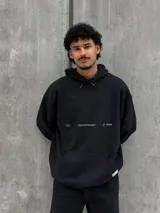 Canguro negro con capucha ajustable con cordones, bolsillo tipo canguro y estampado frontal con el texto "Crafted Project" y símbolos gráficos.