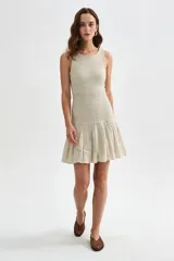 Vestido corto beige sin mangas con cuerpo de nido de abeja elástico y falda corta acampanada con vuelo.