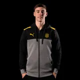 Buzo con cierre frontal y capucha, diseño de bloques de color en negro y gris, con detalles en amarillo en los hombros. Incluye logo de Puma y escudo del Club Atlético Peñarol en el pecho.