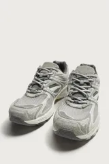 Zapatilla deportiva tipo running color marrón, con parte superior confeccionada en combinación de piezas de malla, gamuza y material sintético. Posee suela con volumen y diseño irregular.
