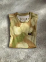 Remera Columbia de manga corta con estampado de camuflaje personalizado inspirado en Endor de Star Wars. Cuenta con cuello redondo, insignia de la Alianza Rebelde en el pecho y tecnología Omni-Shade™ UPF 50 para protección solar.