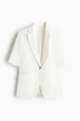 Blazer blanco de sarga con manga corta, botonadura sencilla con un botón, solapas de muesca y bolsillos delanteros ribeteados.
