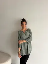 Blusa verde de viscosa con textura sutil, escote en V con botón frontal y mangas tres cuartos de corte holgado.