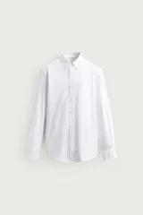Camisa de corte regular fit confeccionada en tejido de algodón, color blanco, con cuello abotonado y manga larga.
