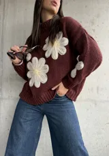 Sweater de punto color chocolate con diseño de flores grandes en relieve en color crema y centro amarillo. Presenta cuello alto, mangas largas y corte holgado.