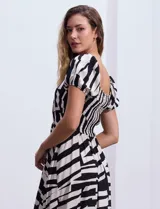 Vestido midi de rayón y lino con estampado geométrico en blanco y negro, escote cuadrado, mangas cortas con elástico y cintura elastizada.