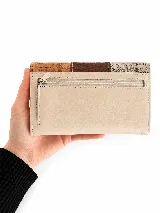 Billetera de cuero Valdez, de diseño estructurado y diseño tricolor en tonos beige, marrón oscuro y suela, con solapa frontal texturizada y placa metálica con el logo de la marca.