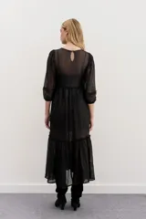 Vestido largo de tul negro con bordados de lentejuelas y canutillos, mangas tres cuartos abullonadas, cintura fruncida y falda con volado en el ruedo.