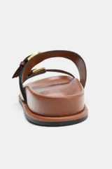 Sandalia plana de cuero color marrón, con dos tiras ajustables con hebillas metálicas doradas y suela de goma.