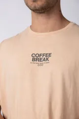 Remera de algodón con efecto lavado, color beige, de corte holgado y manga corta. Presenta un estampado pequeño en el pecho con la frase 'Coffee Break' y un estampado grande en la espalda.
