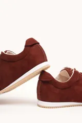 Zapatilla de gamuza color bordó con cordones bicolores, interior de cuero vacuno y suela de caucho blanca y beige.