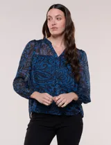 Blusa de silueta holgada y caída fluida, confeccionada en gasa liviana con estampado paisley en tonos azules y negros. Presenta cuello mao con escote en V, cartera frontal con botones, canesú con frunces y mangas largas con puños elastizados.