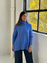 Sweater de punto color azul, con cuello alto acanalado, mangas largas y diseño holgado con costuras verticales decorativas.