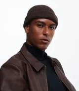 Gorro tipo fisherman de tejido acrílico con textura acanalada, diseño corto y etiqueta pequeña con logo en el frente.