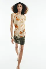 Vestido corto sin mangas de cuello redondo, con estampado tie-dye en tonos beige, naranja y verde oscuro. Presenta un lazo para atar en la cintura y cierre trasero con cremallera oculta.