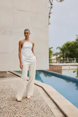 Pantalón de tiro alto color crudo, de pernera recta con detalle de bandas laterales desflecadas.