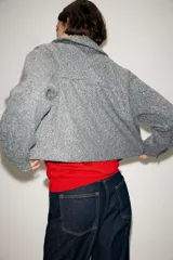 Cazadora de textura suave con cuello solapa, manga larga y cierre frontal con cremallera metálica. Presenta dos bolsillos de plastrón con solapa en la parte delantera.